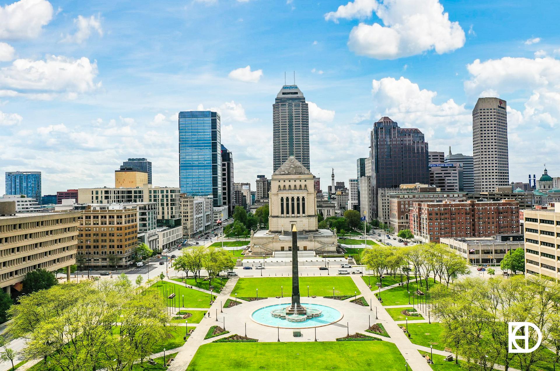 Aerial view of Indiana World War Memorial and Veterans' Memorial Plaza with downtown Indianapolis skyline behind.