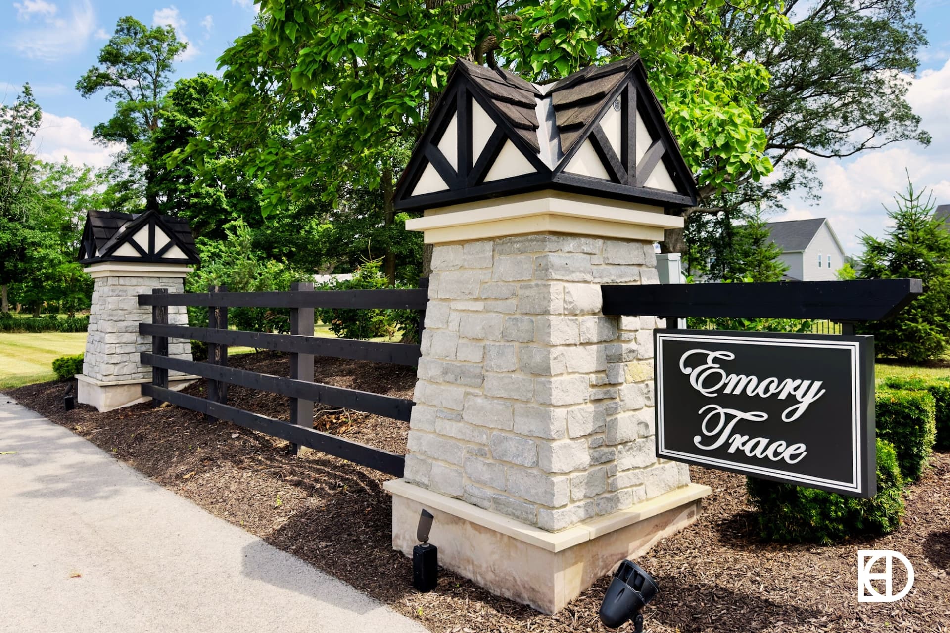 Entrance sign of Emory Trace with stone column and dark wood fence.