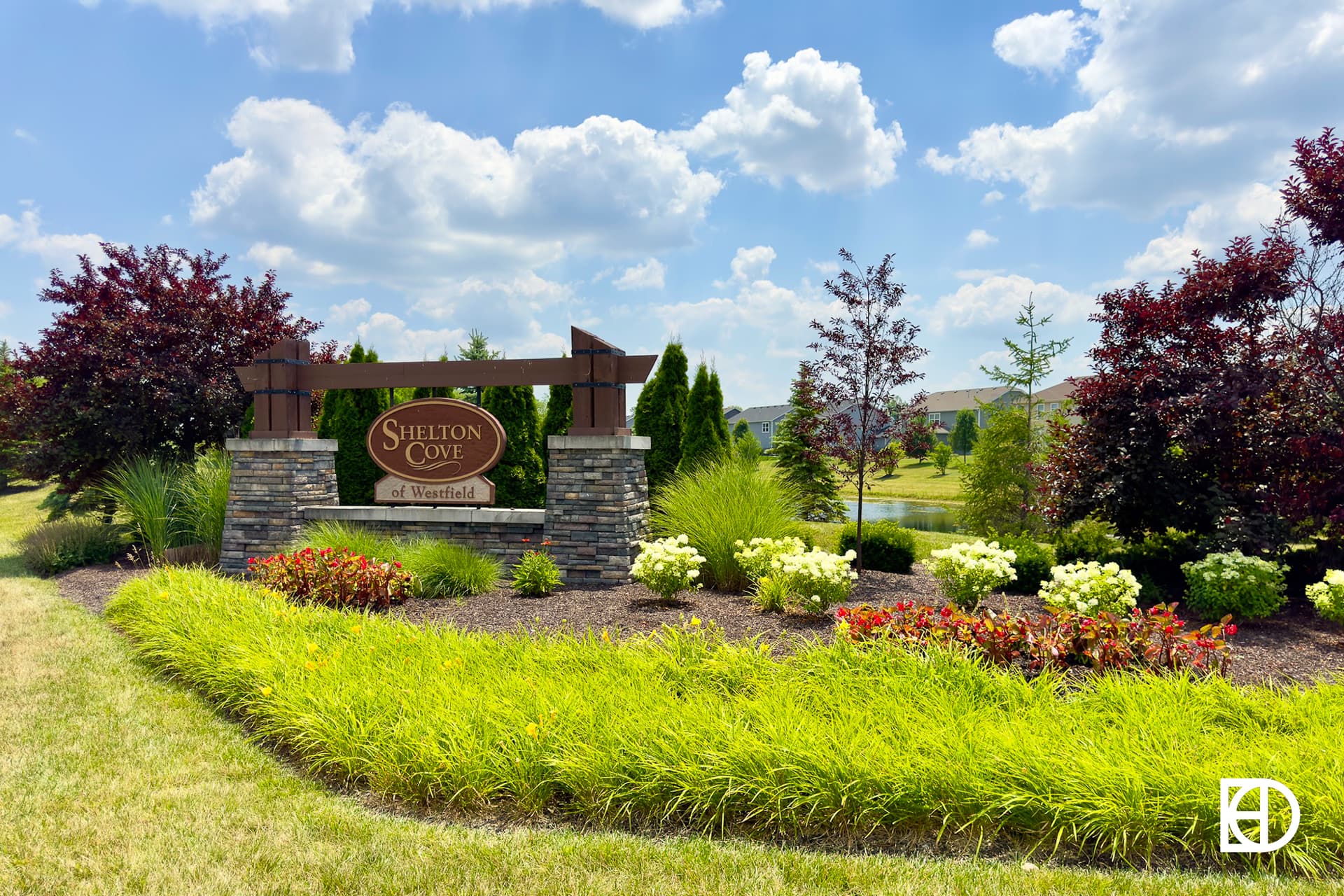 Grasses and flowers with stone and wood entrance sign for Shelton Cove in the background. 