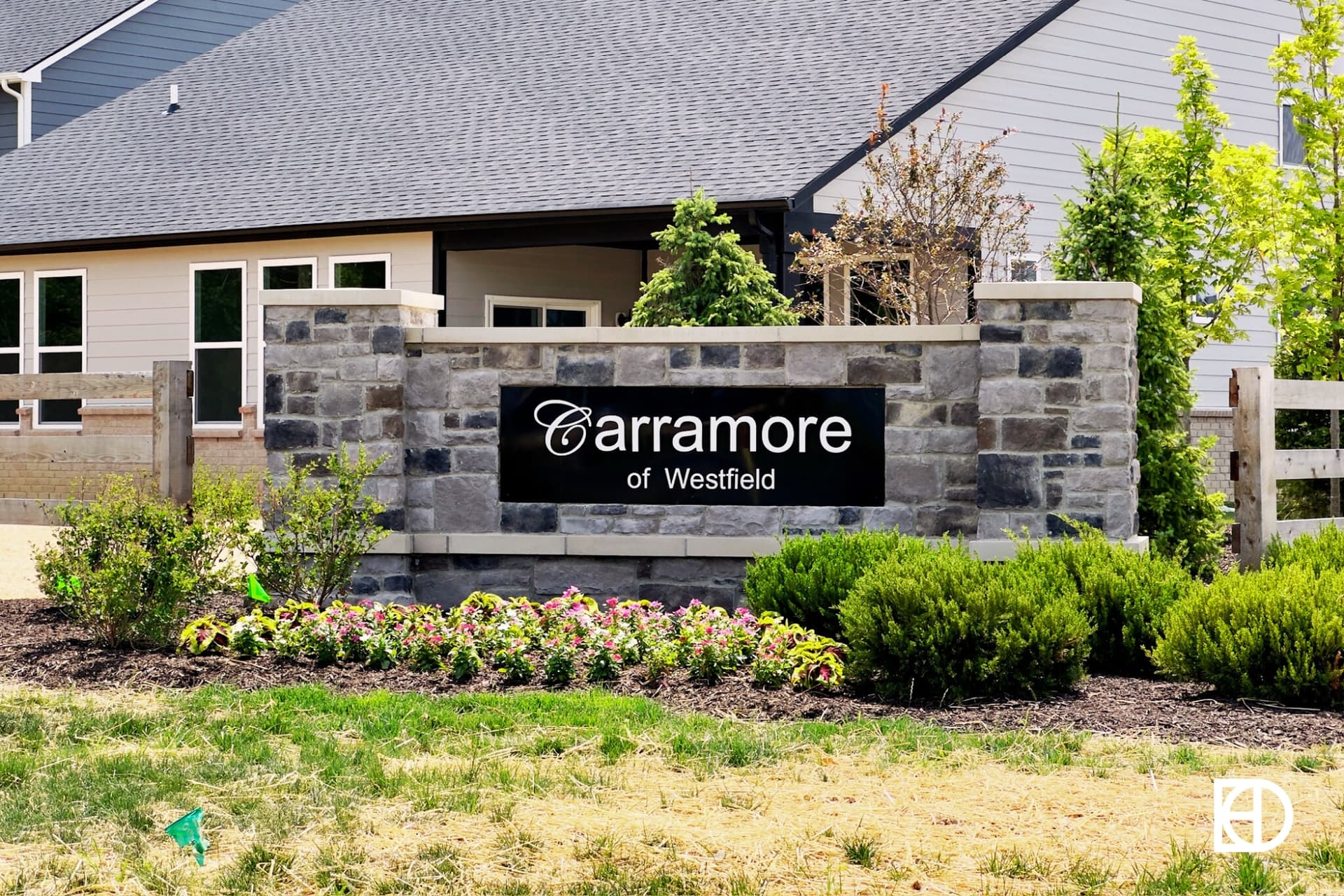 Entrance sign to Carramore neighborhood with black sign on stone half wall.