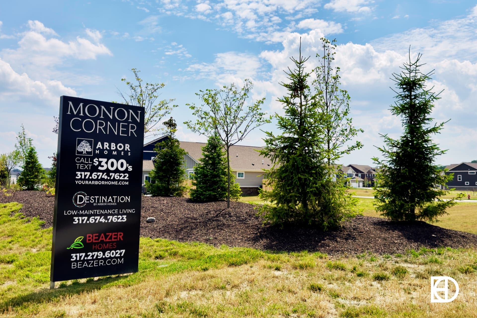 Photo of builder advertisement sign among tree lined edge of neighborhood in Monon Corner.