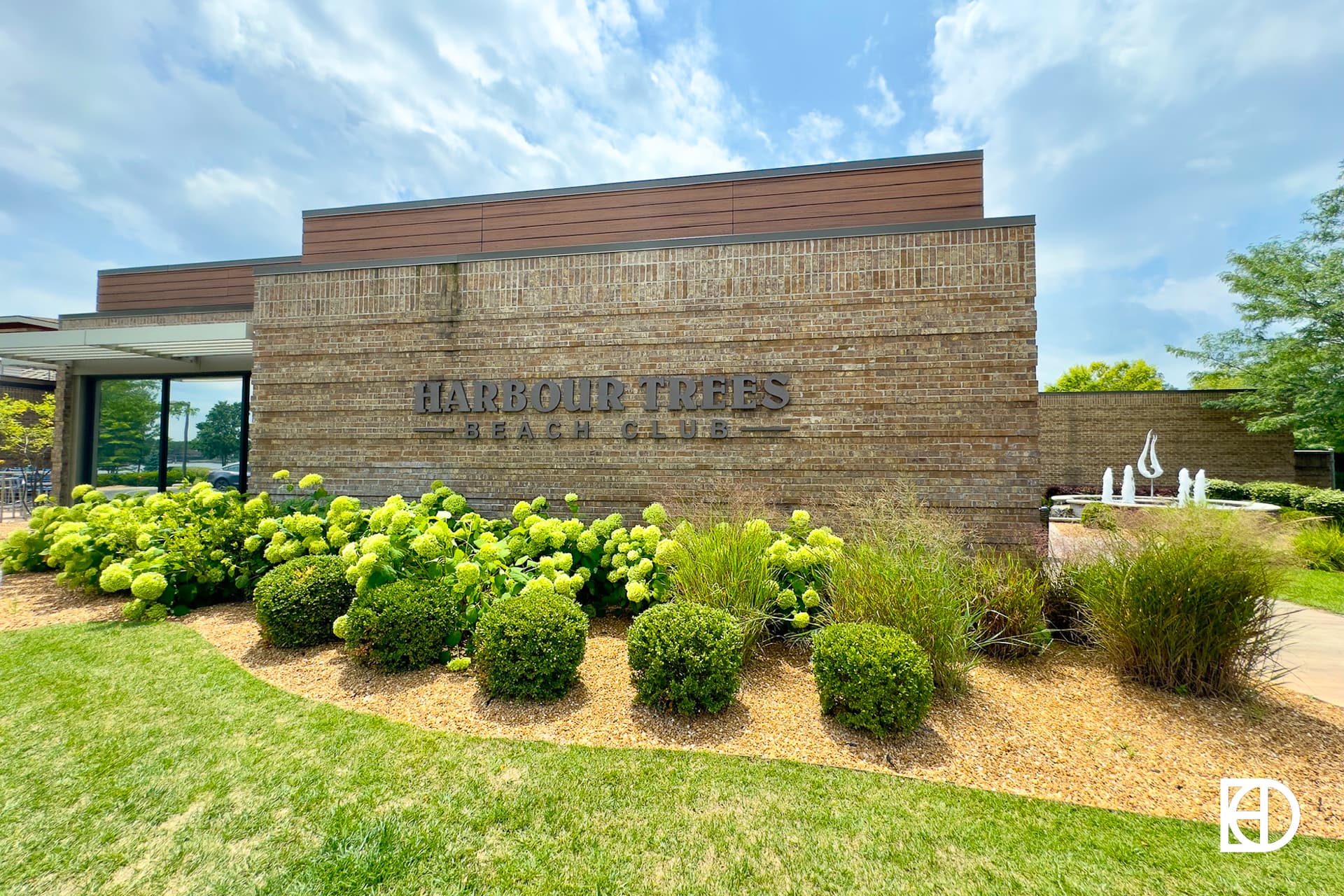 Exterior photo of Harbour Trees Beach Club, showing signage and landscaping