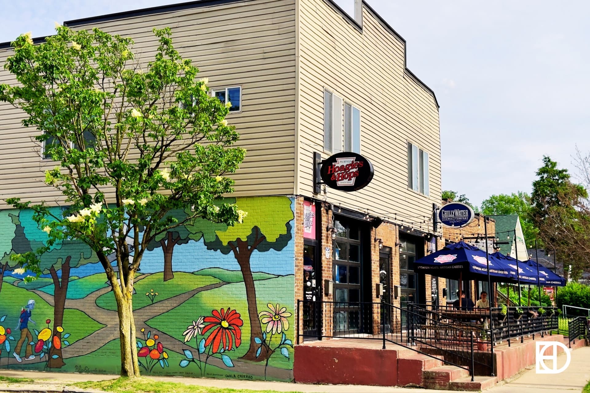 Exterior photo of Hoagies & Hops, showing patio, entrance, and mural 